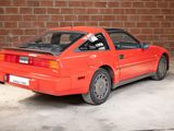 a red car parked in front of a brick wall