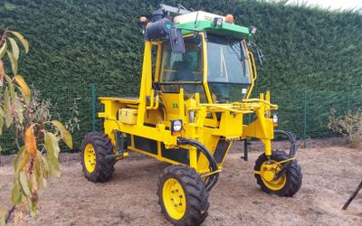 un tracteur jaune garé sur la terre battue