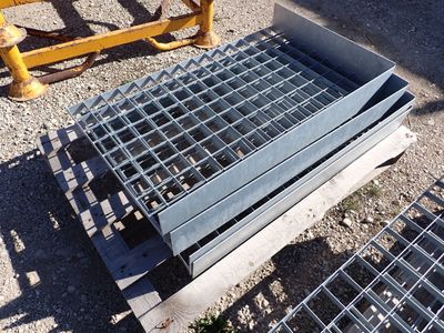 a metal grate laying on the ground next to a yellow fence