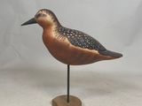 a small bird that is standing on a wooden stand