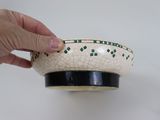 a hand that is holding a bowl on a table