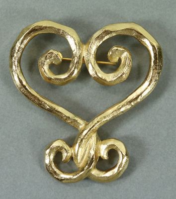 un gros plan d'une broche en forme de cœur ornée de volutes