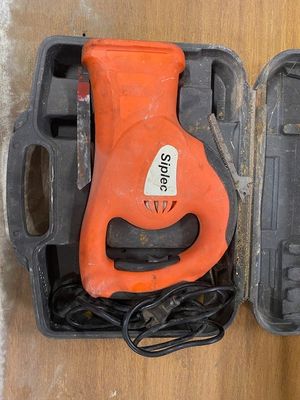 an orange corded drill in a case on a table
