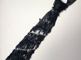 une cravate noire nouée contre un mur blanc