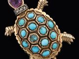 a close up of a turtle broochle with a purple stone in its shell