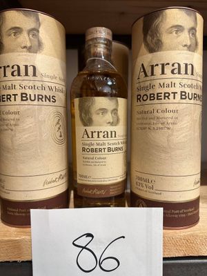 trois bouteilles de whisky posées sur une étagère dans un magasin, avec une étiquette de prix