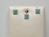 une paire de boucles d'oreilles ornées de pierres vertes et de diamants sur fond blanc