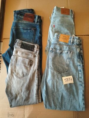 Deux paires de jeans sont posées sur une boîte en carton sur laquelle est accrochée une étiquette de prix.