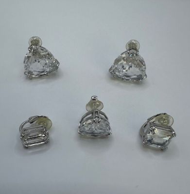 quatre pièces en argent et en verre transparent sont disposées sur une surface blanche