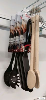 Plusieurs ustensiles de cuisine sont suspendus à un support dans une cuisine