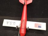 a small red airplane with a chain attached to it