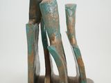 bronze sculpture of a pair of shoes and a vase on a stand
