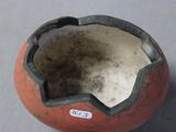 a small red and black vase with a tag on it