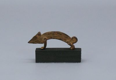 une petite sculpture en bronze représentant un chien, posée sur un bloc de bois