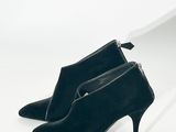 une paire de chaussures noires à talons hauts posée sur une surface blanche