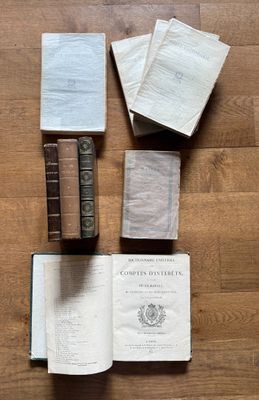 several old books on a wooden floor with one open and the other closed