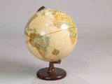 un petit globe terrestre posé sur un socle, sur une table