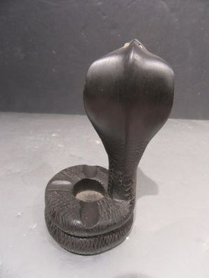 statue d'un cobra sur une surface blanche, avec un fond noir