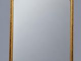 a gold framed mirror on a wall with a gray background