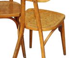 two wooden chairs sitting next to each other on a white surface