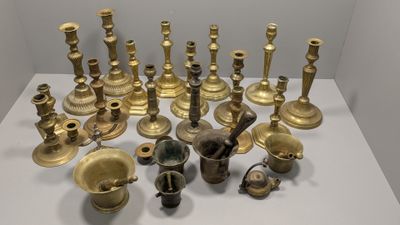 many different types of brass candles on a white table