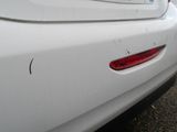 the rear end of a white car with a sticker on it ' s bumper