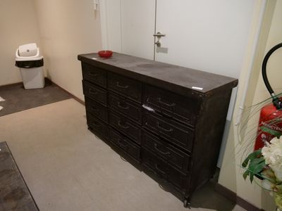 une commode noire dans une pièce équipée de toilettes et d'un lavabo