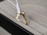 une bague en or sertie d'un diamant, posée dans une boîte