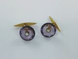 une paire de boutons de manchette violets et dorés sur un fond blanc