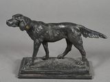 statue en bronze représentant un chien, posée sur un socle en marbre, sur fond gris
