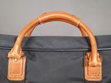 a close up of a black bag with a brown handle