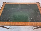 an old wooden table with a green glass top and legs