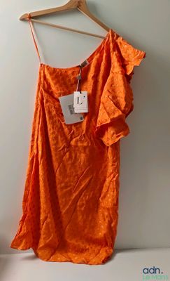 une robe orange suspendue à un cintre accroché au mur