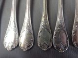 six silver spoons are lined up in a row on a table