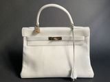 a white leather handbag on a black background