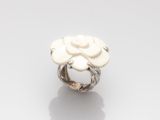 une image représentant une bague ornée d'une fleur blanche posée sur une surface blanche