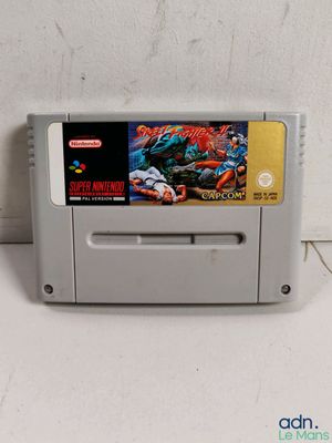 Un vieux jeu Nintendo est posé sur une table près d'un mur blanc.