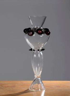 un vase en verre contenant des olives noires, posé sur une table