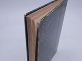 an open book with a black cover sitting on top of a white surface