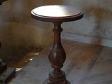 a small wooden table with a white top on a stone floor