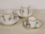 three cups and saucers sitting on a table with a white background
