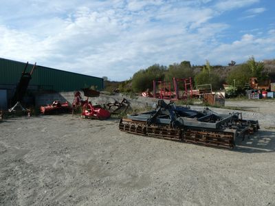 une photo montrant un tracteur et d'autres engins sur un terrain en terre battue