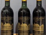 four bottles of wine are lined up on a wooden table