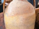 un grand vase marron posé par terre à côté d'autres pots