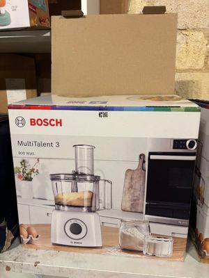 Des cartons contenant des appareils électroménagers sont empilés sur une étagère dans un magasin