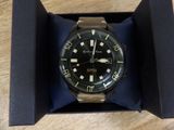 a black and gold watch in a box on a wooden table