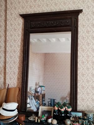 un miroir posé sur une table, sur laquelle se trouve un chapeau
