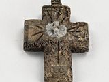 une vieille croix en métal posée sur une surface blanche, avec un diamant au centre