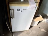 a small refrigerator that has a roll of toilet paper on top of it