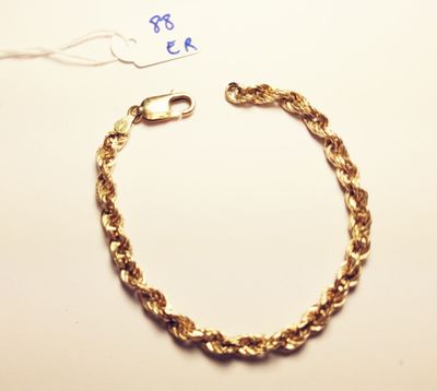 a gold chain bracelet with a clasp on a white surface